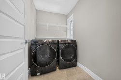 Dedicated laundry area featuring a tiled floor, light gray walls, a window for natural light, and wire shelving for storage - 