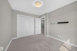 Interior room with light gray walls, gray carpeting, white baseboards, and white bi-fold closet doors - 