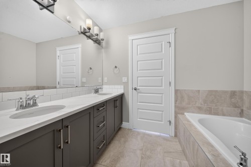 Double vanity featuring dark wood-finish cabinetry, quartz countertops, and dual undermount sinks - 4620 Alwood Way Sw, Edmonton, AB - Indoor Photo Showing Bathroom