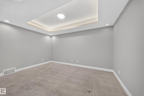 Recessed tray ceiling with integrated lighting, complemented by additional recessed lighting and light gray wall finishes - 4620 Alwood Way Sw, Edmonton, AB - Indoor Photo Showing Other Room