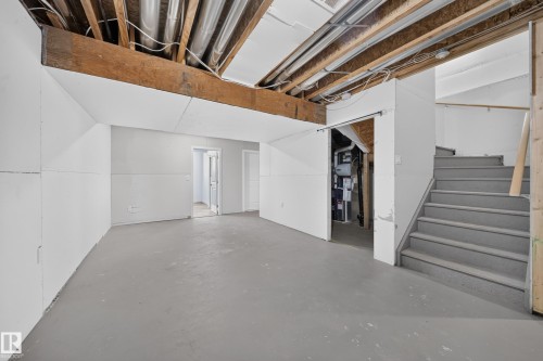Unfinished lower level featuring exposed ceiling joists, utility piping, painted concrete flooring, and partial wall coverings - 4620 Alwood Way Sw, Edmonton, AB - Indoor Photo Showing Basement