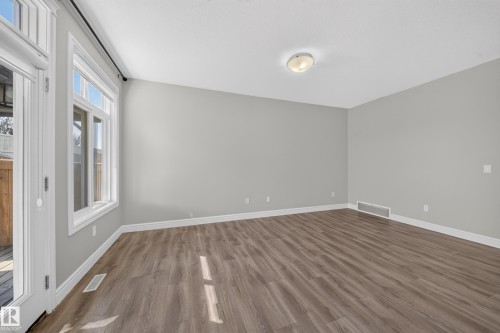 Spacious interior room featuring wood-finish flooring, light gray wall paint, white baseboards, and a white ceiling with a flush-mount light fixture - 4620 Alwood Way Sw, Edmonton, AB - Indoor Photo Showing Other Room