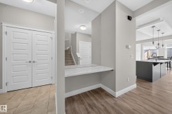 Built-in desk nook with a white marble-look surface, light gray walls, and wood-finish flooring - 