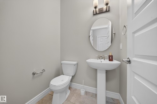 Pedestal sink with an oval mirror and wall-mounted light fixture - 4620 Alwood Way Sw, Edmonton, AB - Indoor Photo Showing Bathroom