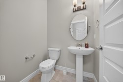 Pedestal sink with an oval mirror and wall-mounted light fixture - 
