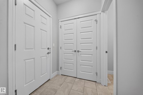 Entry area featuring light-toned tile flooring, white paneled doors, and contemporary silver-finish hardware - 4620 Alwood Way Sw, Edmonton, AB - Indoor Photo Showing Other Room