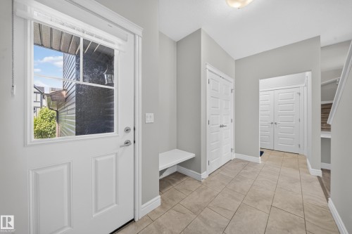 Entryway featuring light neutral wall paint, tile flooring, a built-in bench, and white panel doors - 4620 Alwood Way Sw, Edmonton, AB - Indoor Photo Showing Other Room