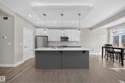 Spacious kitchen featuring a large island with a light-toned countertop, white cabinetry, stainless steel appliances, and a tile backsplash - 