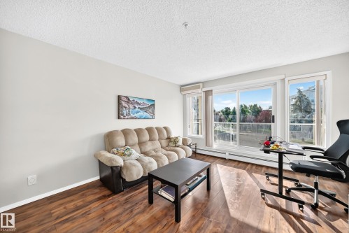 Living area featuring wood-finish flooring, light-toned wall paint, and a textured ceiling - #201 9760 174 St Nw, Edmonton, AB - Indoor Photo Showing Living Room
