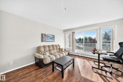 Living area featuring wood-finish flooring, light-toned wall paint, and a textured ceiling - 