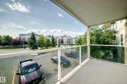 Private balcony with a textured concrete floor, glass panel railing, and a white soffit ceiling - 