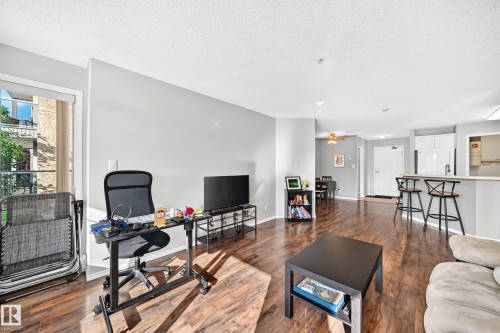 Open-concept living area featuring wood-finish flooring, light gray wall tones, and recessed lighting - #201 9760 174 St Nw, Edmonton, AB - Indoor Photo Showing Living Room