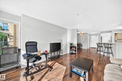 Open-concept living area featuring wood-finish flooring, light gray wall tones, and recessed lighting - 