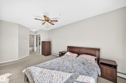 Carpeted bedroom with a ceiling fan light fixture, light gray wall paint, and white baseboards - 