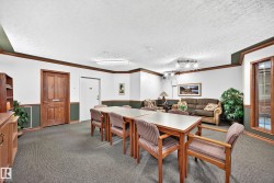 Spacious common area featuring textured carpet flooring, white walls with dark green wainscoting, and wood-finish trim throughout - 