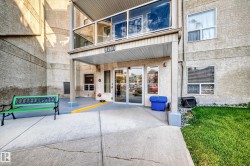 Building entrance featuring glass doors, a covered porch, and a second-story balcony with glass railings - 