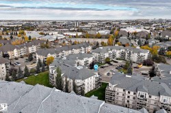 Aerial overview of a multi-building residential complex featuring pitched shingle roofs and multiple balconies - 