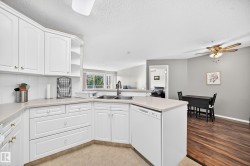 Kitchen featuring white cabinetry with gold-toned hardware, light-toned countertops, and a double basin sink - 