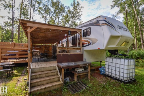 Outdoor wood-frame patio featuring a covered deck, built-in wooden shelving, and a dual-basin utility sink station - 200 12272 Township Road 602, Rural Smoky Lake County, AB 