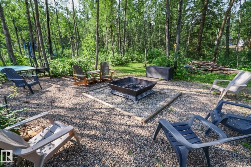 Expansive outdoor fire pit area featuring a gravel base, square metal fire pit, and surrounding natural wooded environment - 200 12272 Township Road 602, Rural Smoky Lake County, AB 
