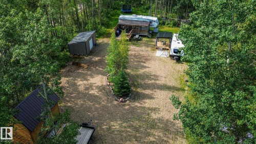Wooded property featuring a gravel drive, a shed with a metal roof, and a small cabin with a dark metal roof - 200 12272 Township Road 602, Rural Smoky Lake County, AB 