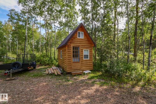 Log cabin structure featuring a dark roofline, wood-frame windows, and a glass-paneled entry door - 200 12272 Township Road 602, Rural Smoky Lake County, AB 