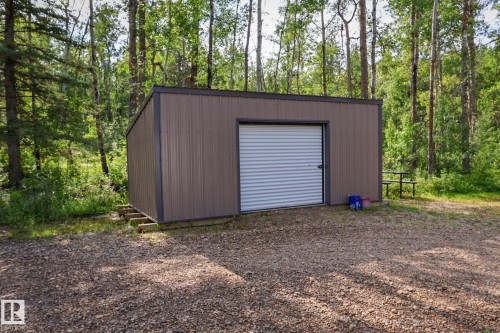 Brown metal utility building with a roll-up garage door, set on a gravel base - 200 12272 Township Road 602, Rural Smoky Lake County, AB 
