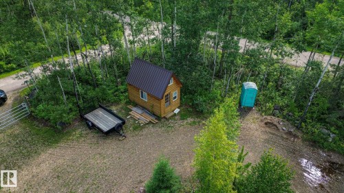 Wood cabin structure with a metal roof, set within a wooded area - 200 12272 Township Road 602, Rural Smoky Lake County, AB 