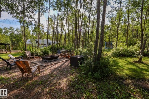 Wooded outdoor gathering area featuring a central fire pit on a gravel base - 200 12272 Township Road 602, Rural Smoky Lake County, AB 