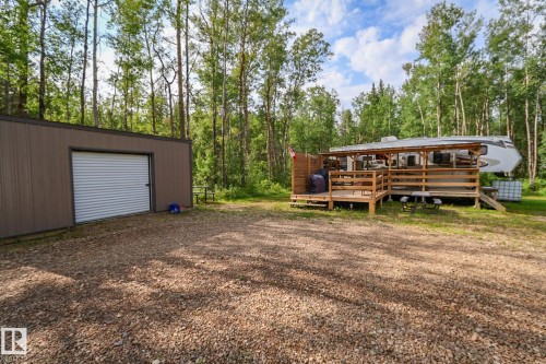 Gravel driveway leading to a brown metal-sided outbuilding with a roll-up garage door - 200 12272 Township Road 602, Rural Smoky Lake County, AB 