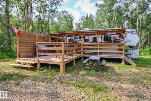 Expansive outdoor wooden deck featuring a slatted privacy wall, multiple entry points, and a covered section - 200 12272 Township Road 602, Rural Smoky Lake County, AB 