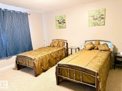 Bedroom featuring light-colored wall paint, light-toned carpeting, and a window with blue curtains - 