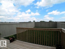 Wood-finish deck overlooking a fenced backyard with green grass - 