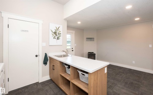 Utility area featuring light wood-finish cabinetry, a stainless steel sink, and a white countertop - 62503A Hwy 769, Rural Barrhead County, AB - Indoor