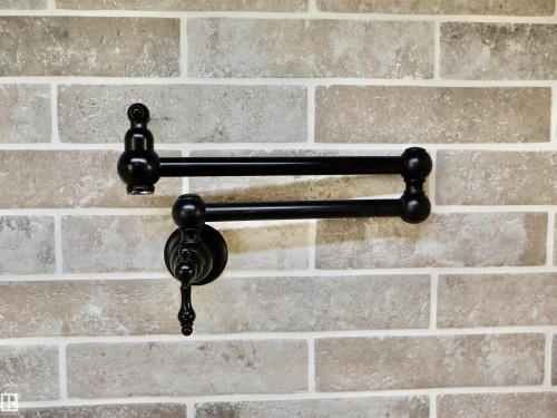 Matte black pot filler faucet with a decorative handle, set against a light-toned brick-patterned backsplash with white grout - 62503A Hwy 769, Rural Barrhead County, AB - Indoor