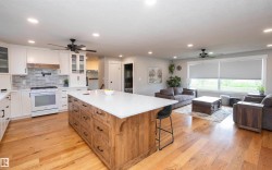 Open-concept kitchen and living area featuring wood-finish flooring, recessed lighting, and ceiling fans - 