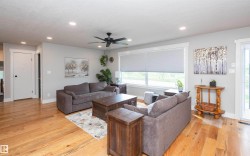 Spacious living area featuring wood-finish flooring, recessed lighting, and a ceiling fan - 