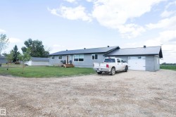 Ranch-style residence featuring a gray exterior, dark metal roofing, and multiple windows - 