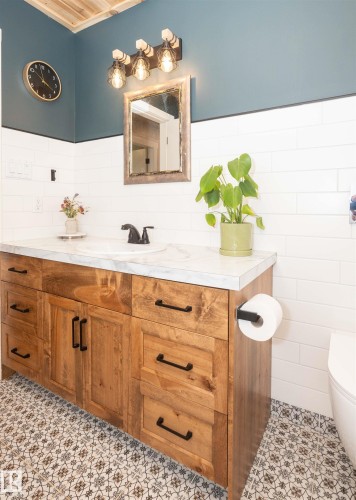 Wood-finish vanity with ample storage drawers and black hardware, topped with a white countertop and integrated sink - 62503A Hwy 769, Rural Barrhead County, AB - Indoor Photo Showing Bathroom