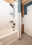 Contemporary bathroom featuring a tub/shower combination, white marble-look wall tiling, and a patterned floor tile - 