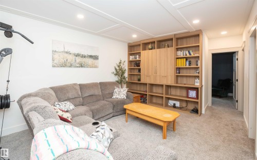 Spacious carpeted room featuring a custom built-in entertainment center with extensive shelving and integrated cabinetry - 62503A Hwy 769, Rural Barrhead County, AB - Indoor Photo Showing Living Room
