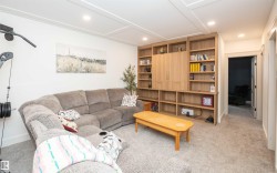 Spacious carpeted room featuring a custom built-in entertainment center with extensive shelving and integrated cabinetry - 
