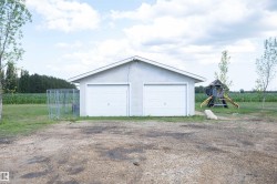 Detached two-car garage with white overhead doors and a neutral exterior finish - 