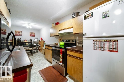 Kitchen featuring wood-finish cabinetry, dark countertops, and tile flooring - #307 6212 180 St Nw, Edmonton, AB - Indoor