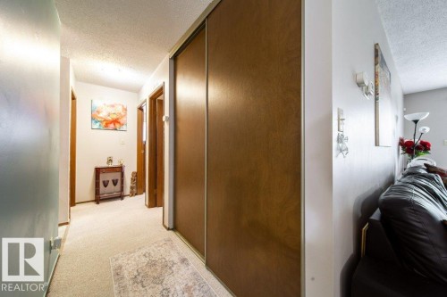 Hallway featuring wood-finish bi-fold closet doors, light-toned carpeting, and wood-finish interior doors - #307 6212 180 St Nw, Edmonton, AB - Indoor Photo Showing Other Room