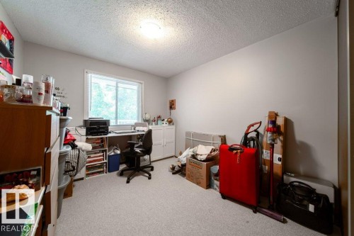 Window with exterior tree scenery, carpet flooring, light-colored walls, and a ceiling-mounted light fixture - #307 6212 180 St Nw, Edmonton, AB - Indoor Photo Showing Office