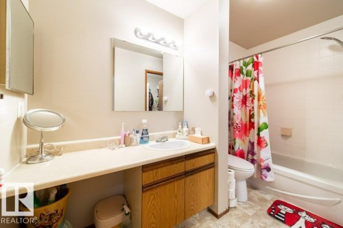 Bathroom with a light-toned vanity featuring a built-in sink and wood-finish cabinetry - #307 6212 180 St Nw, Edmonton, AB - Indoor Photo Showing Bathroom