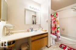 Bathroom with a light-toned vanity featuring a built-in sink and wood-finish cabinetry - 