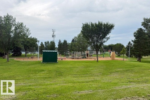 Expansive grassy area featuring a dedicated playground with multiple structures, including swings, slides, and climbing elements - #307 6212 180 St Nw, Edmonton, AB - Outdoor With View