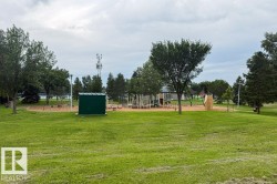 Expansive grassy area featuring a dedicated playground with multiple structures, including swings, slides, and climbing elements - 